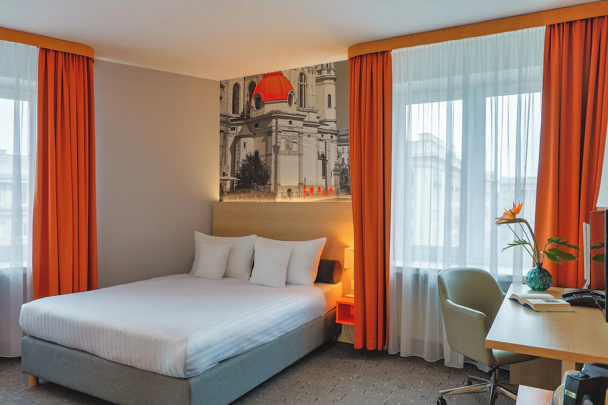 Double room at Hotel MDM with orange curtains and a Warsaw mural