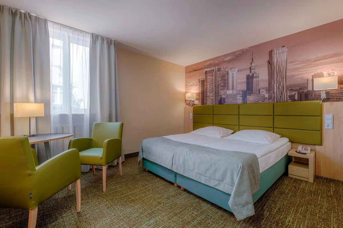 Premium double room at Hotel Reytan with green headboard and Warsaw skyline mural