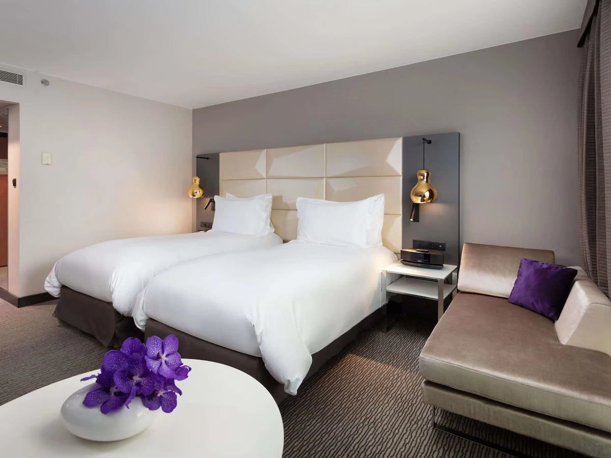 Twin room at Sofitel Warsaw Victoria with upholstered headboard and lounge seating